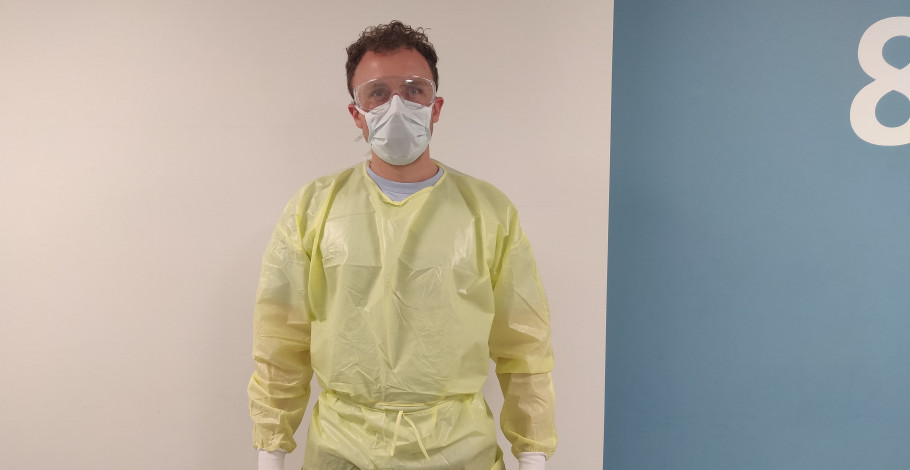 Michael Frikke står med mundbind og plastikkittel på.